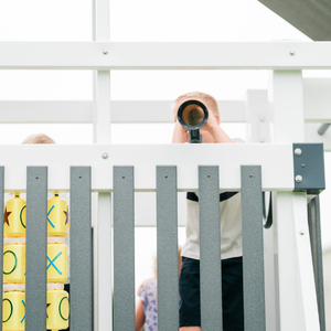 Person taking a photo of a child playing with a toy on a white railing.