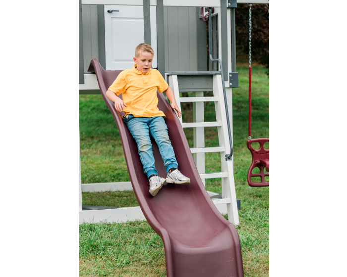 Child sliding down a playground slide in a backyard setting