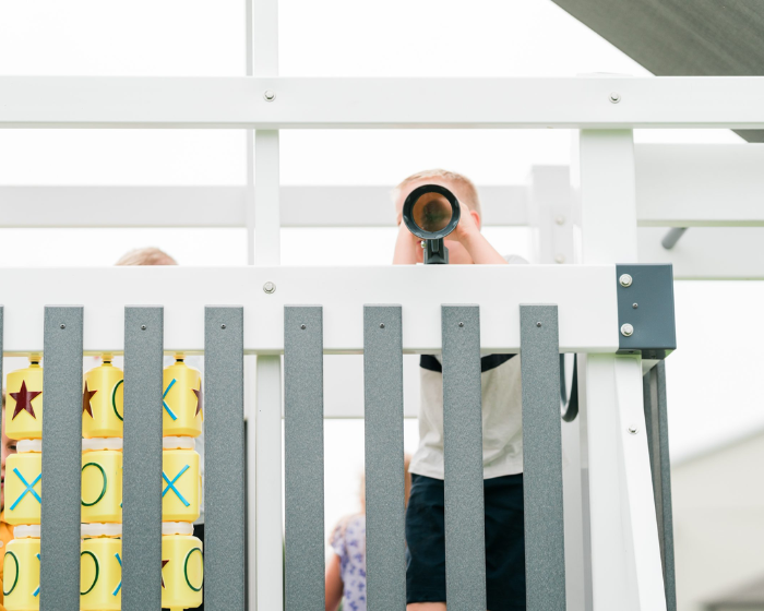Person taking a photo of a child playing with a toy on a white railing.