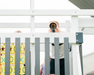Person taking a photo of a child playing with a toy on a white railing.