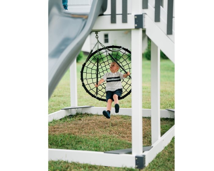 Child playing on a playground swing set with a slide in the background