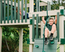 Child climbing on a playground structure with green and beige colors.